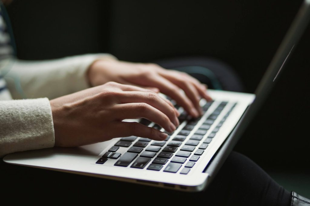 Hands typing on a laptop in the dark